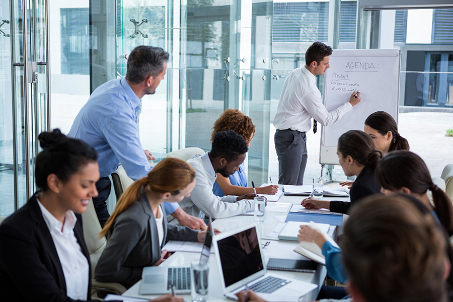 man giving presentation and employees taking notes on their laptops